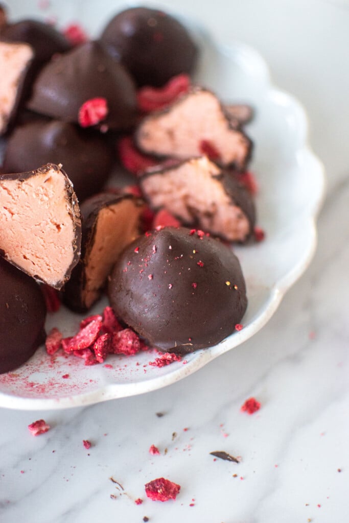 plate of strawberry cream drops on a white marble counter.