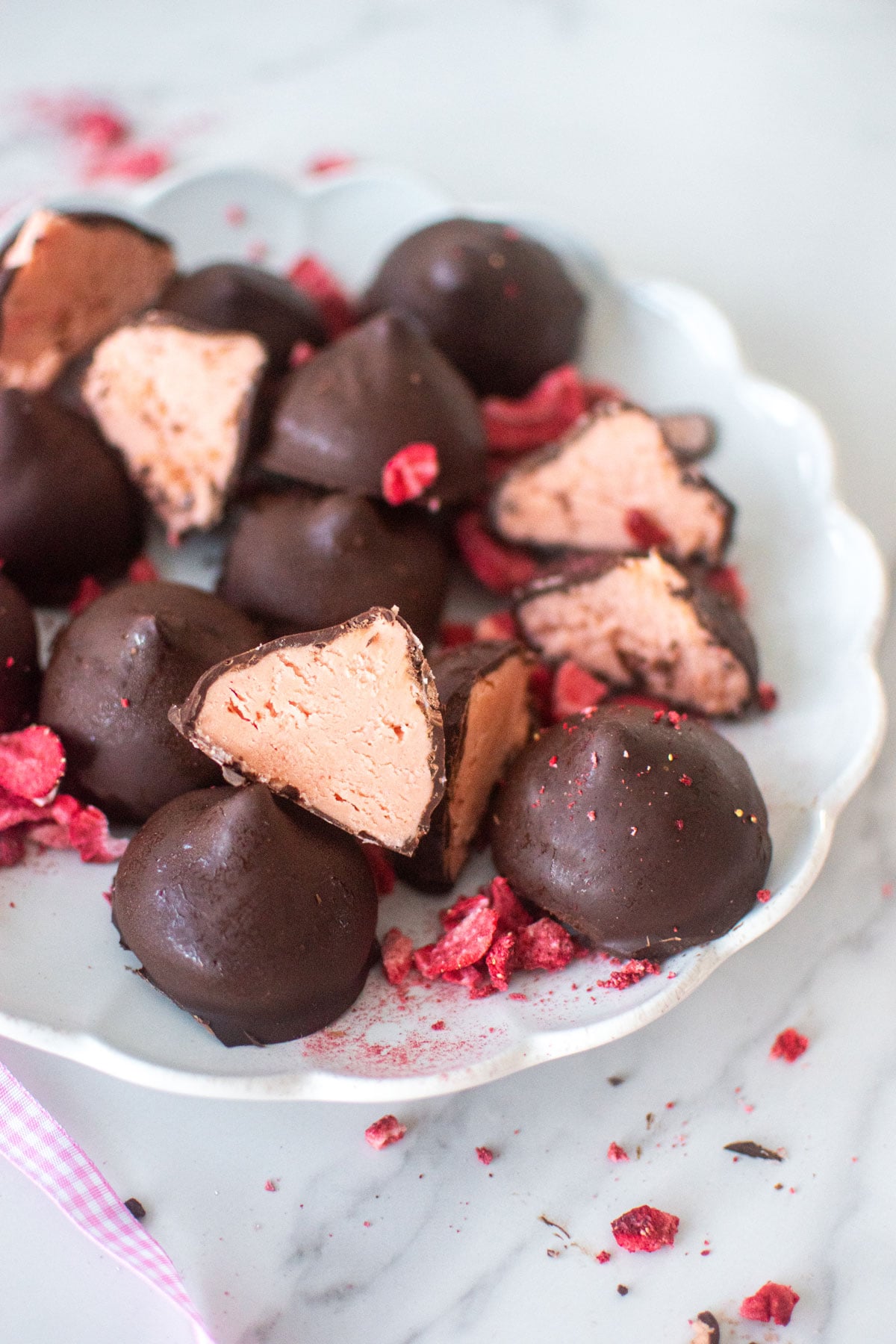 plate of strawberry cream drops on a white marble counter.