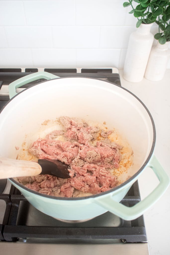 dutch oven on a stovetop with ground turkey being cooked.
