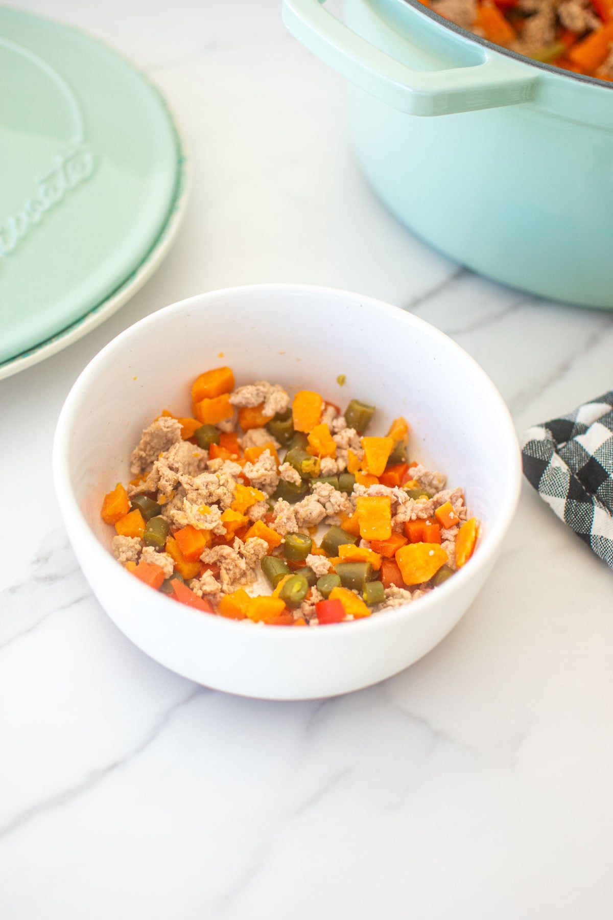 turkey dog food recipe in a white dog bowl on a marble countertop.