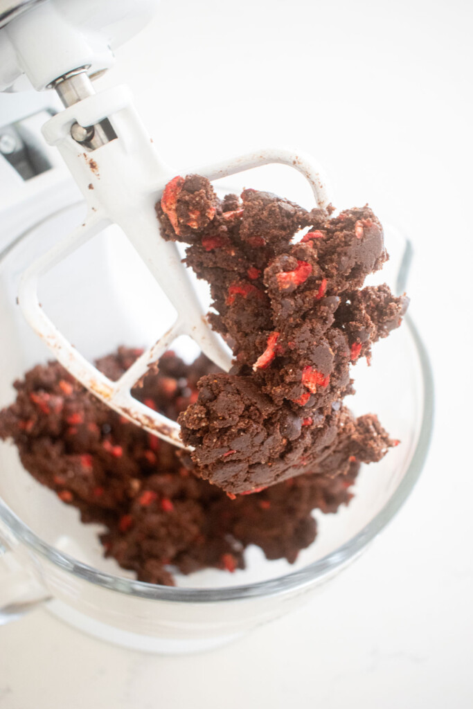 eggless chocolate strawberry cookie dough in a glass mixing bowl on a marble counter.