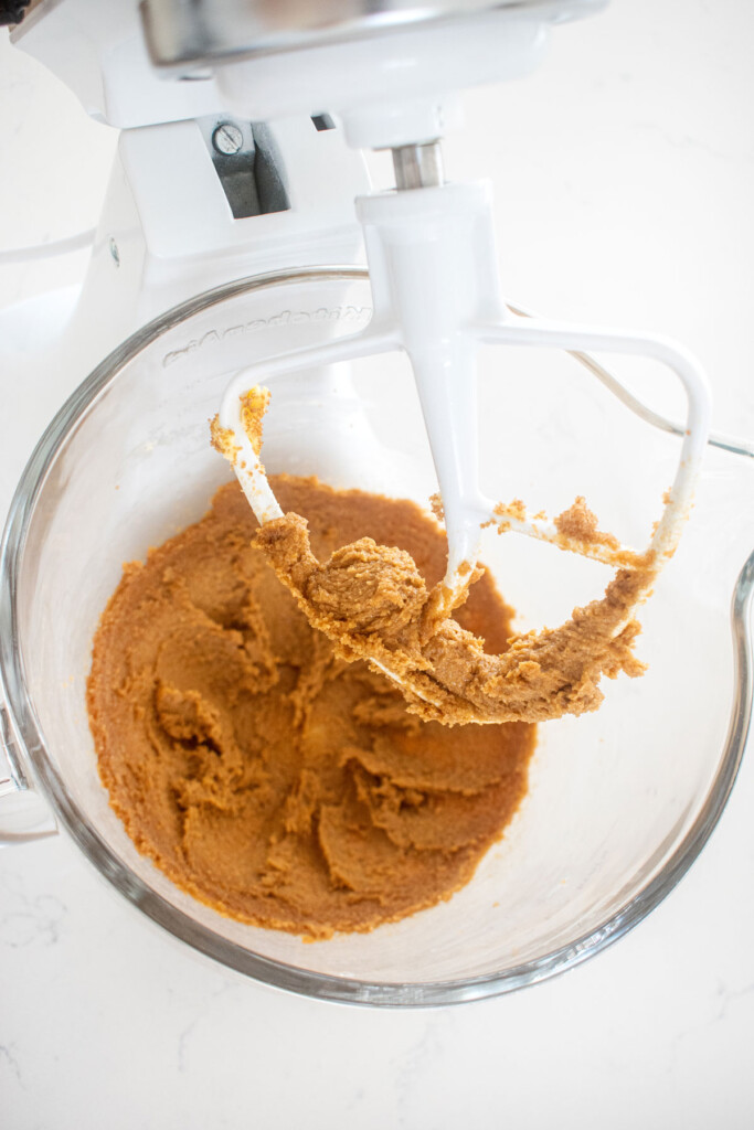 creamed butter and sugar in a glass mixing bowl on a marble counter.