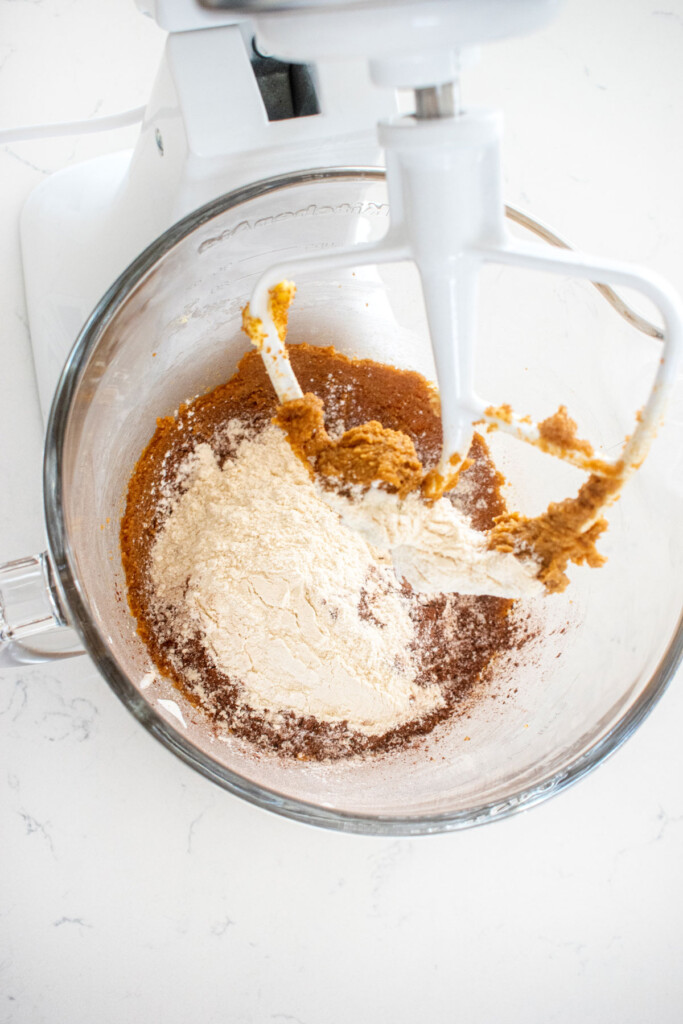 ingredients for eggless cosmic brownie cookie dough in a glass mixing bowl on a marble counter.