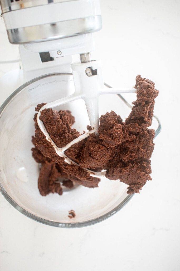 eggless cosmic brownie cookie dough in a glass mixing bowl on a marble counter.