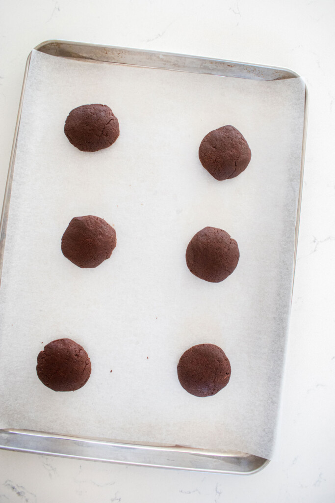 eggless cosmic brownie cookie dough balls on a baking sheet on a marble counter.