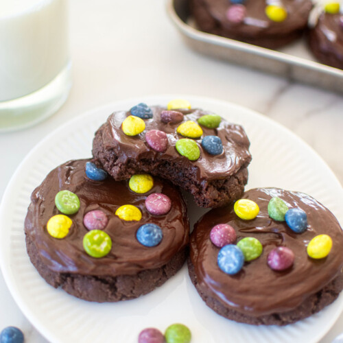 plate of eggless cosmic brownie cookies and a glass of milk on a marble counter.