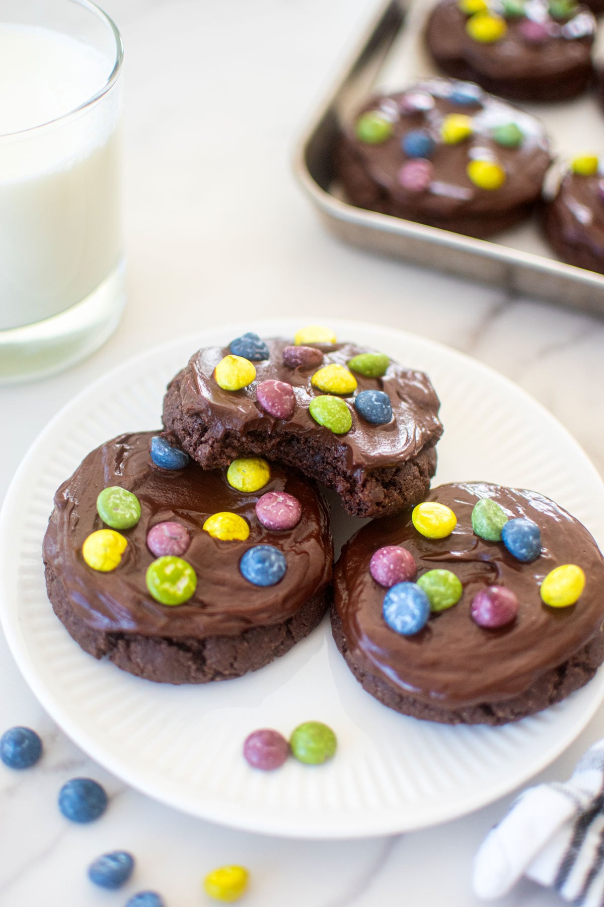 plate of eggless cosmic brownie cookies and a glass of milk on a marble counter.