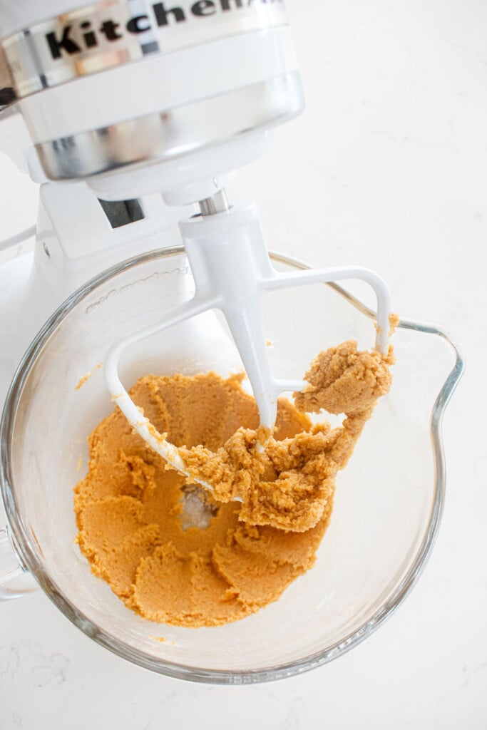 creamed butter and sugar in a glass mixing bowl on a white marble counter.