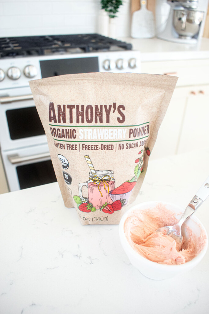 pink frosting with freeze dried strawberry powder on a white marble counter.