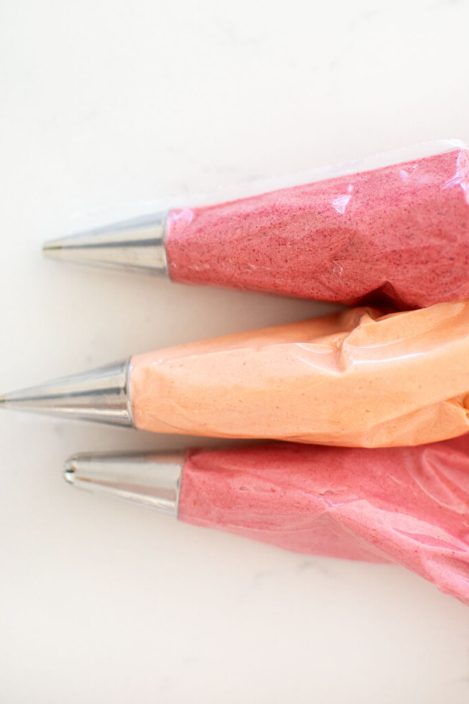 organic pink food coloring in piping bags on a marble counter.