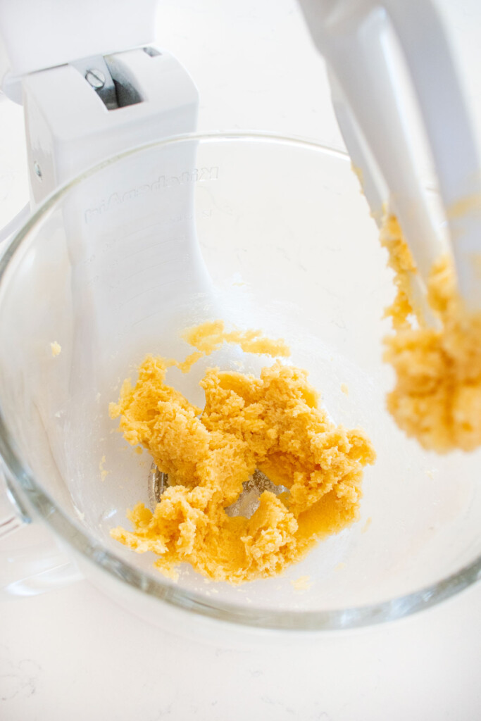 creamed butter and sugar in a glass mixing bowl on a marble counter.