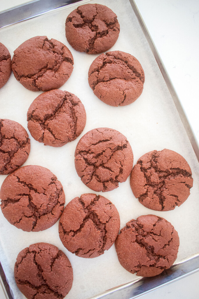 sourdough red velvet cookies without food coloring on a baking sheet on a marble counter.
