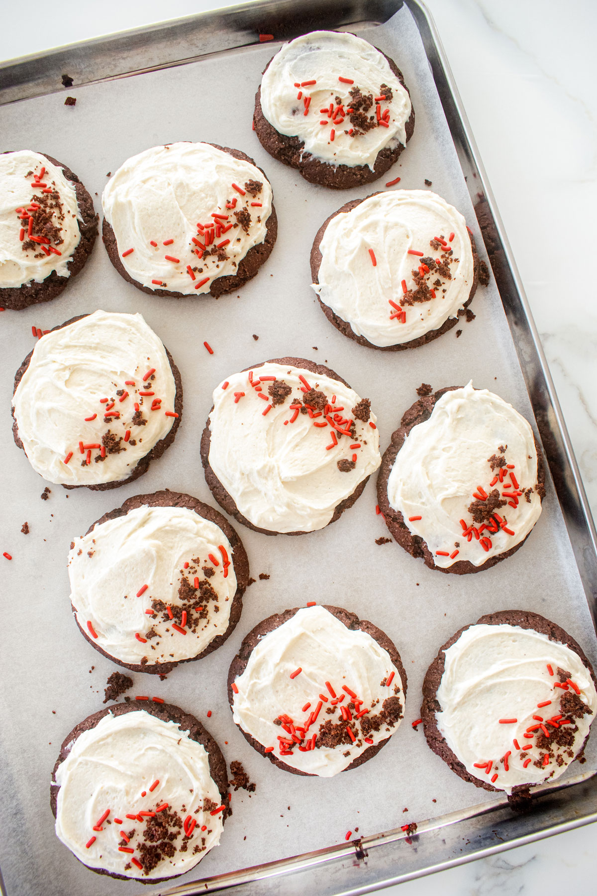 sourdough red velvet cookies without food coloring on a baking sheet on a marble counter.