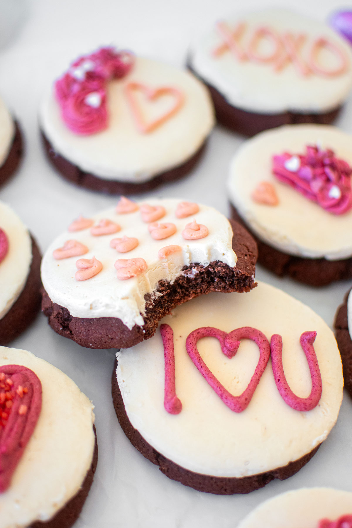 sourdough red velvet cookies with cream cheese frosting decorated with valentine's day decorations on a baking sheet.