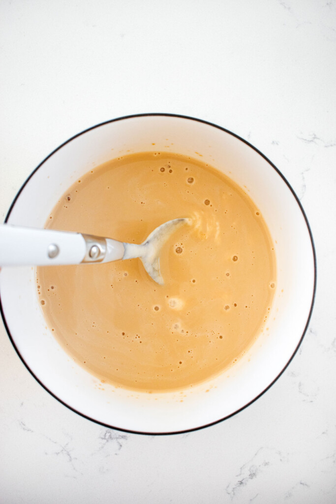 yeast, brown sugar and sourdough discard being stirred in a small bowl on a marble countertop.