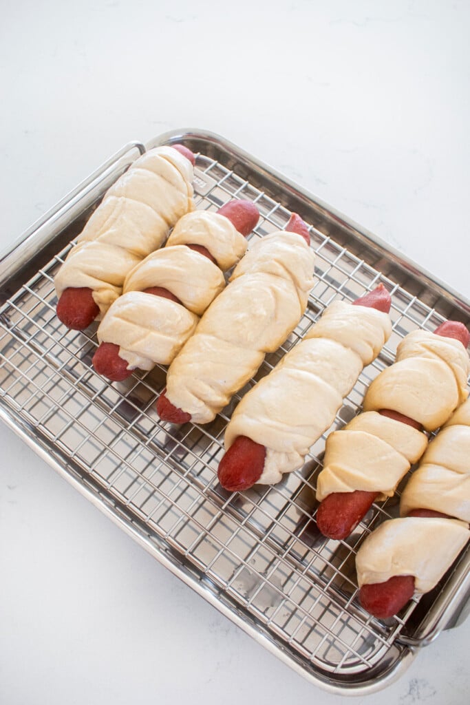 sourdough hot dog pretzel buns wrapped on a roasting rack on a marble countertop.