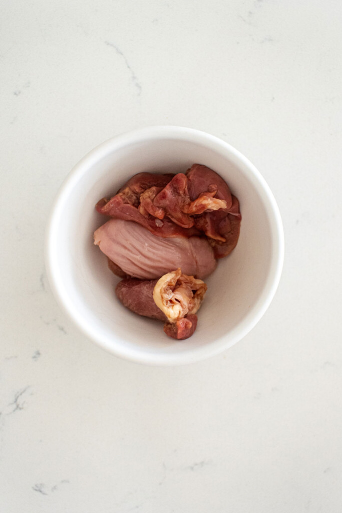 raw chicken giblets in a bowl on a white countertop.