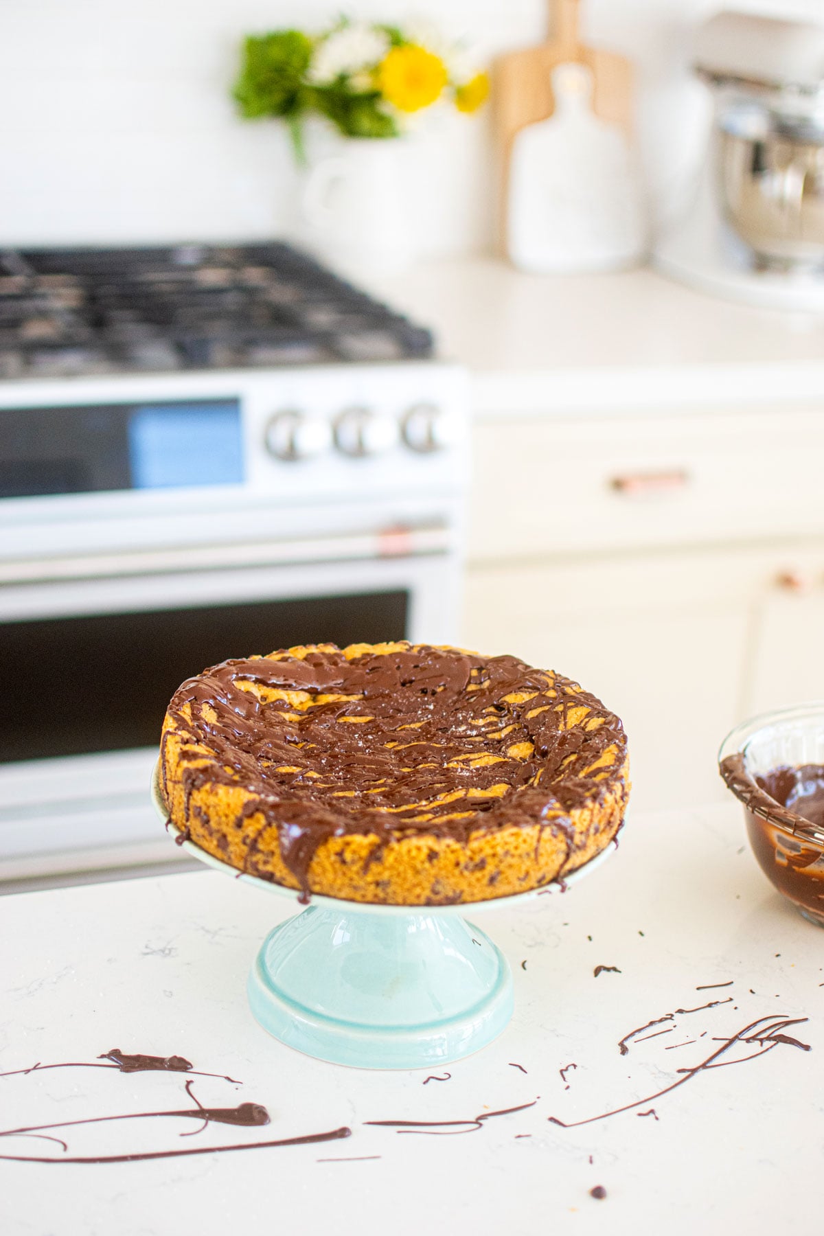 eggless chocolate chip cookie cake on a green cake pedestal on the kitchen counter.