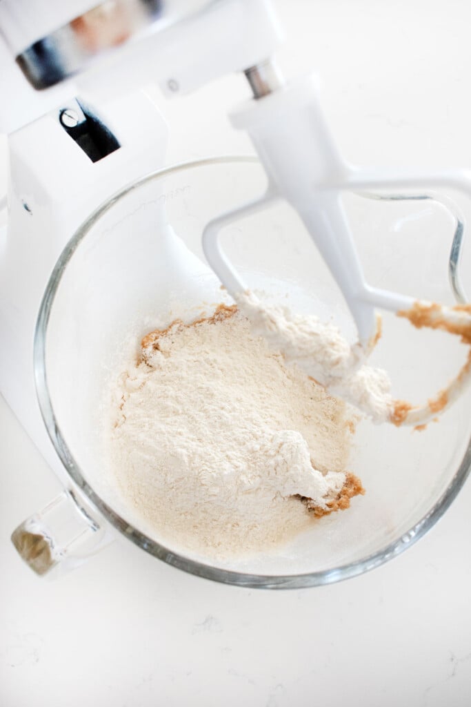 ingredients for eggless chocolate chip cookie dough in a stand mixing bowl on a marble counter.
