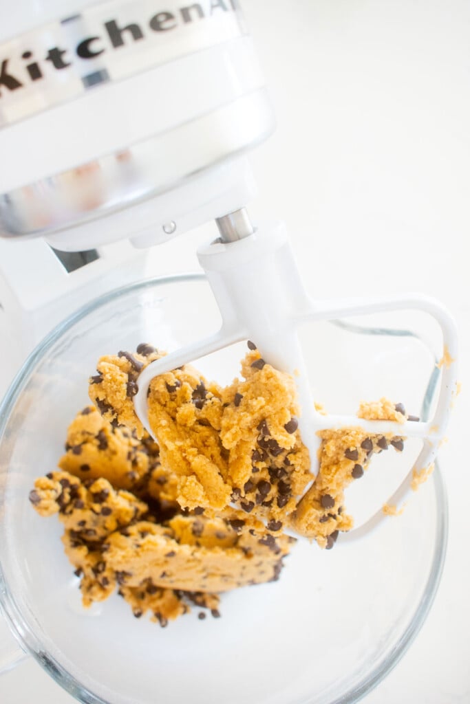 eggless chocolate chip cookie dough in a stand mixing bowl on a marble counter.