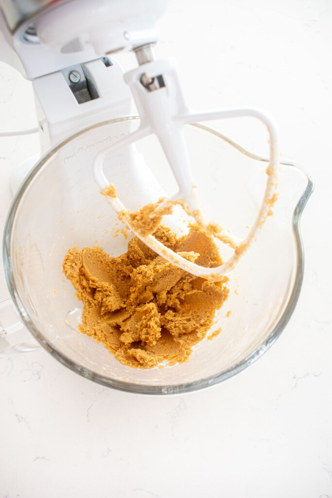 creamed butter and sugar in a glass mixing bowl on a marble counter.