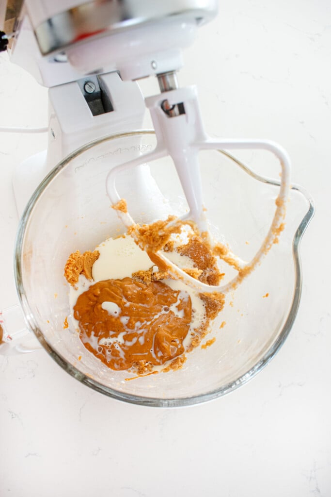 wet ingredients for eggless monster cookies in a glass mixing bowl on a marble counter.