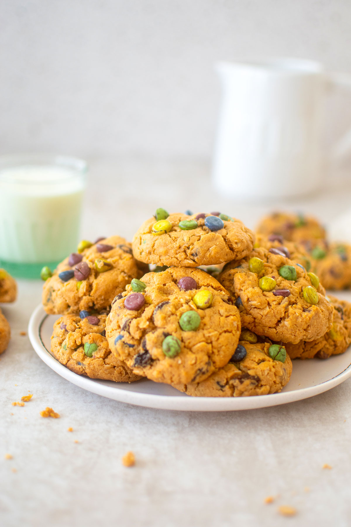 plate of eggless monster cookies with a glass of milk on a table.