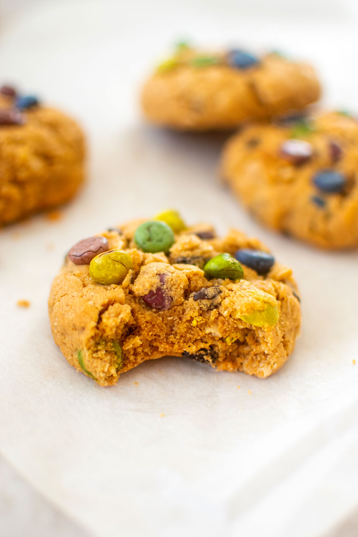 eggless monster cookie with a bite taken out on a piece of parchment paper.