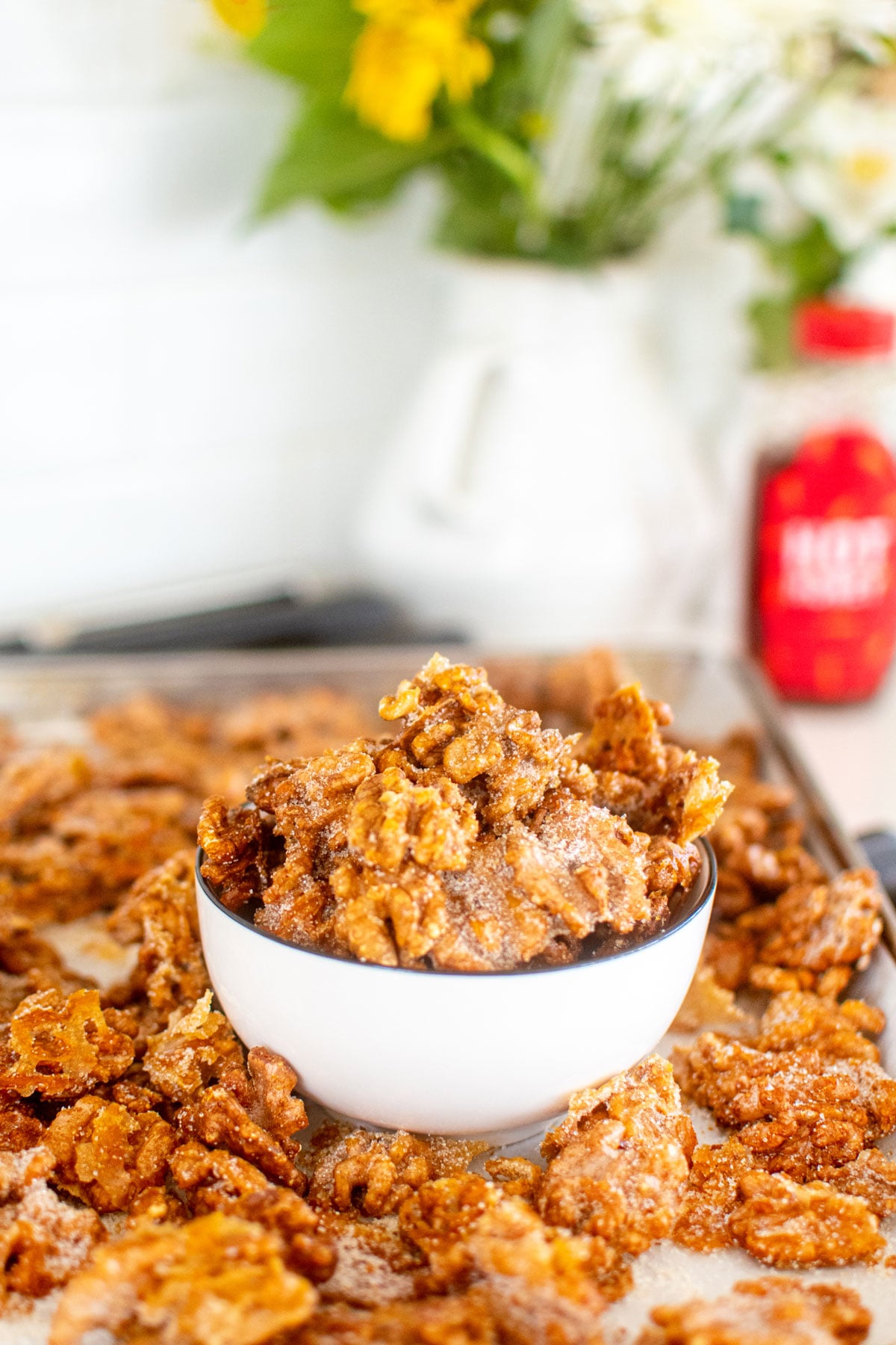 hot honey roasted walnuts in a bowl on a baking sheet sitting on the stovetop.