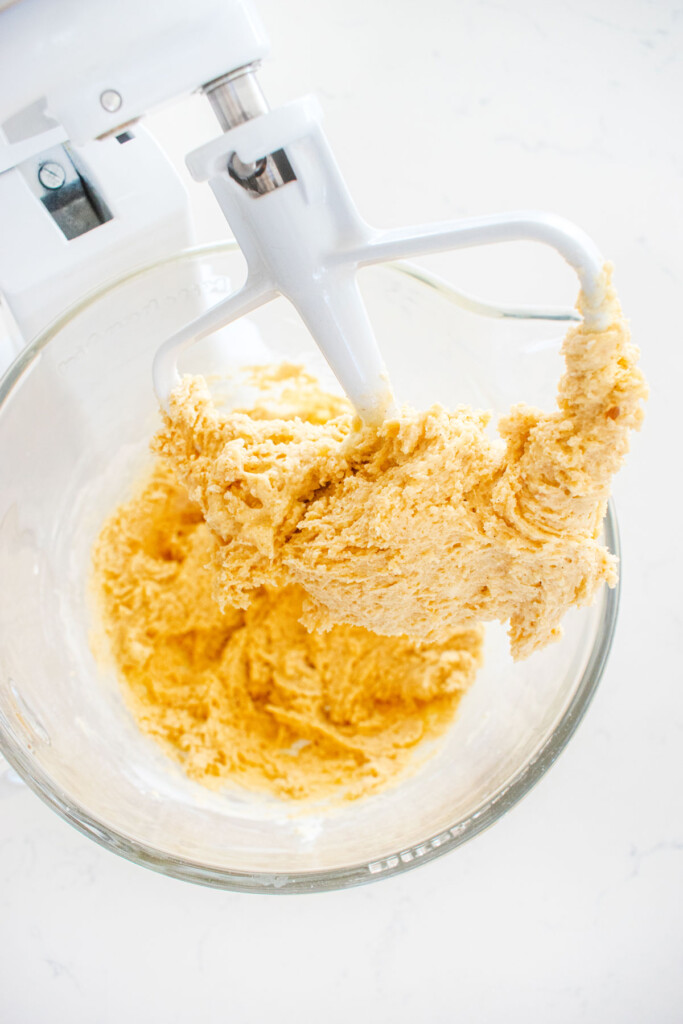 sugar cookie dough in a glass mixing bowl on a white marble counter.