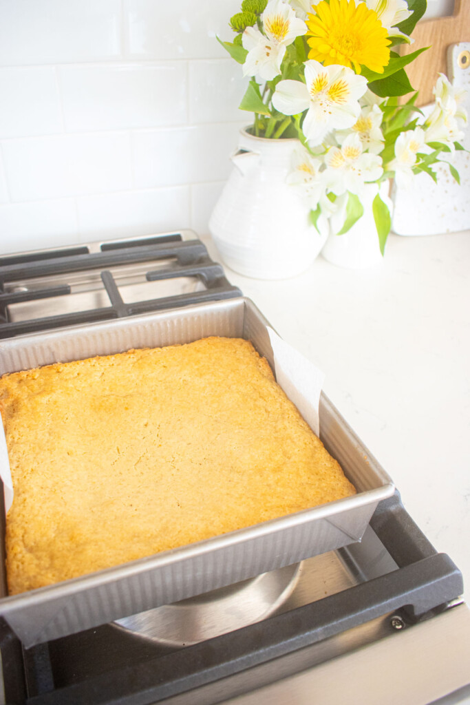 baked sugar cookie bars in a square baking pan on a white marble counter.
