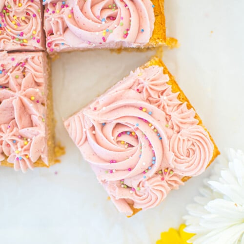 organic sugar cookie bars with frosting on a white marble counter.