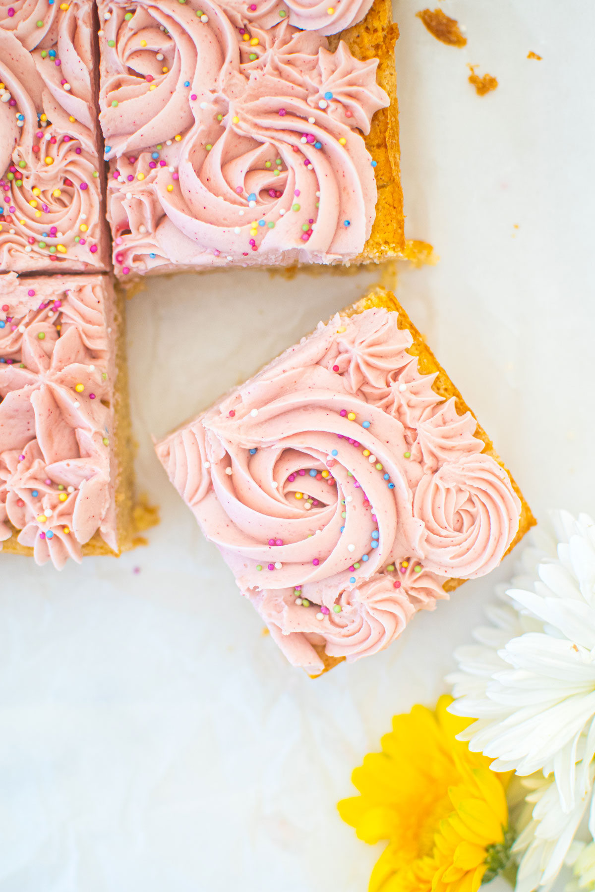 organic sugar cookie bars with frosting on a white marble counter.