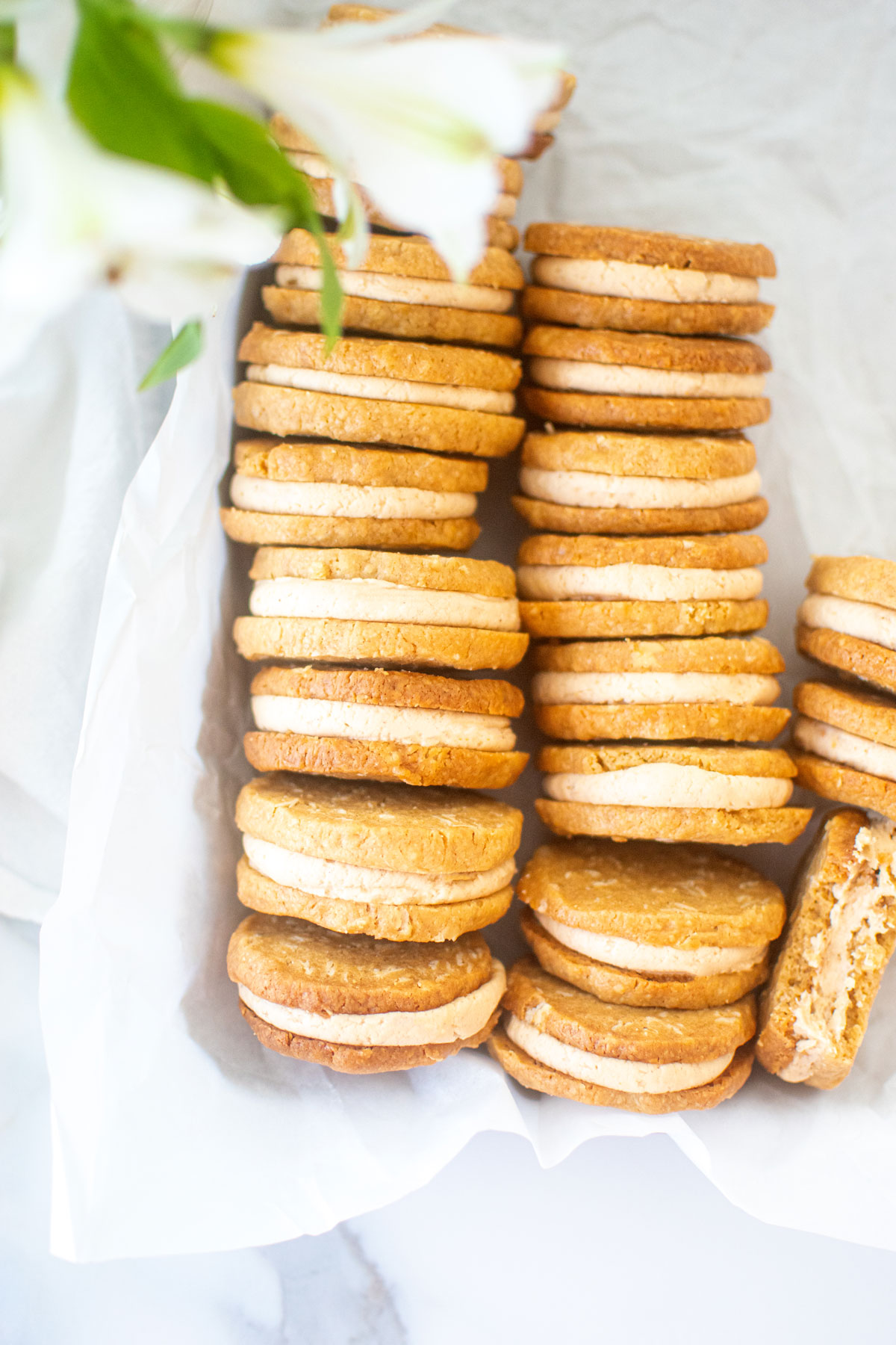 peanut butter oatmeal sandwich cookies in a baking sheet on a marble counter.
