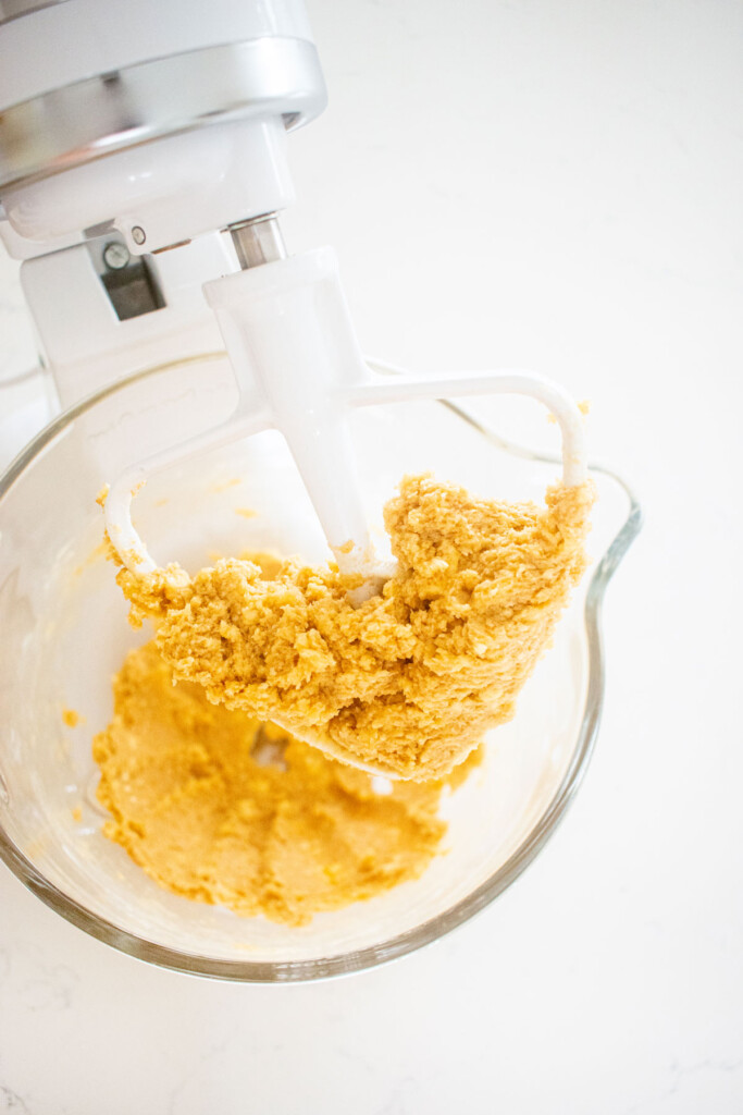 peanut butter oatmeal cookie dough in a stand mixing bowl on a marble counter.