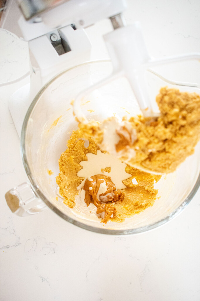 ingredients for peanut butter oatmeal cookies in a stand mixing bowl on a marble counter.