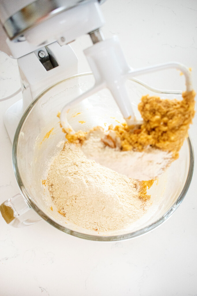 ingredients for peanut butter oatmeal cookies in a stand mixing bowl on a marble counter.