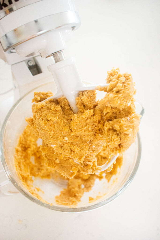 peanut butter oatmeal cookie dough in a glass mixing bowl on a marble counter.