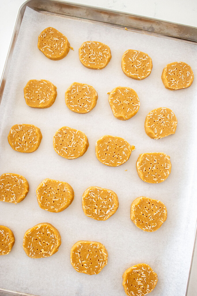 peanut butter oatmeal cookie dough slices on a baking sheet on a white marble counter.