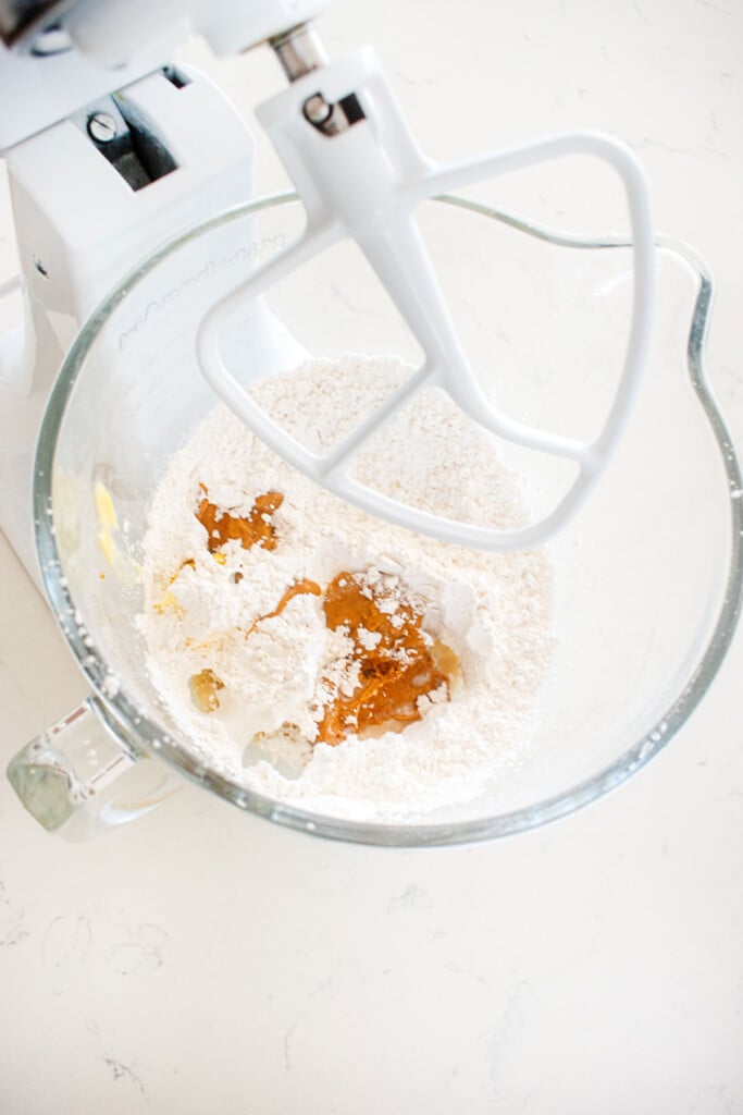 ingredients for peanut butter frosting in a glass mixing bowl on a white marble counter.
