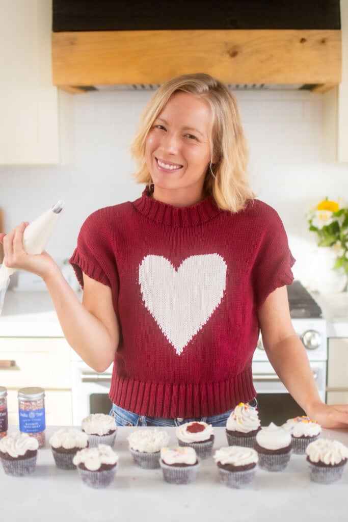 woman frosting cupcakes at the kitchen counter.