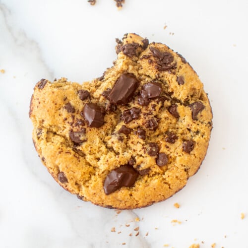 vegan sourdough chocolate chip cookie with a bite taken out on a marble counter.