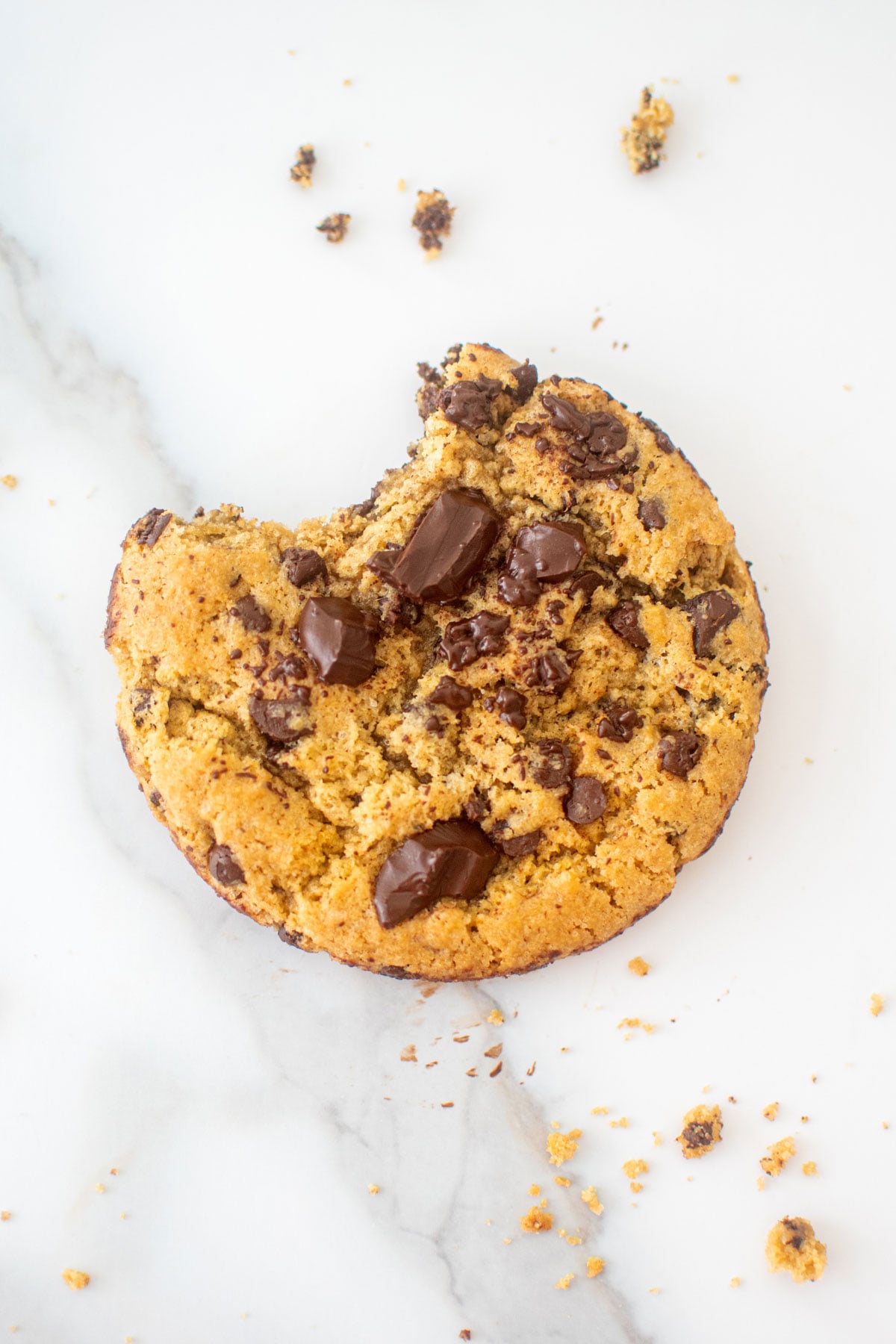 vegan sourdough chocolate chip cookie with a bite taken out on a marble counter.