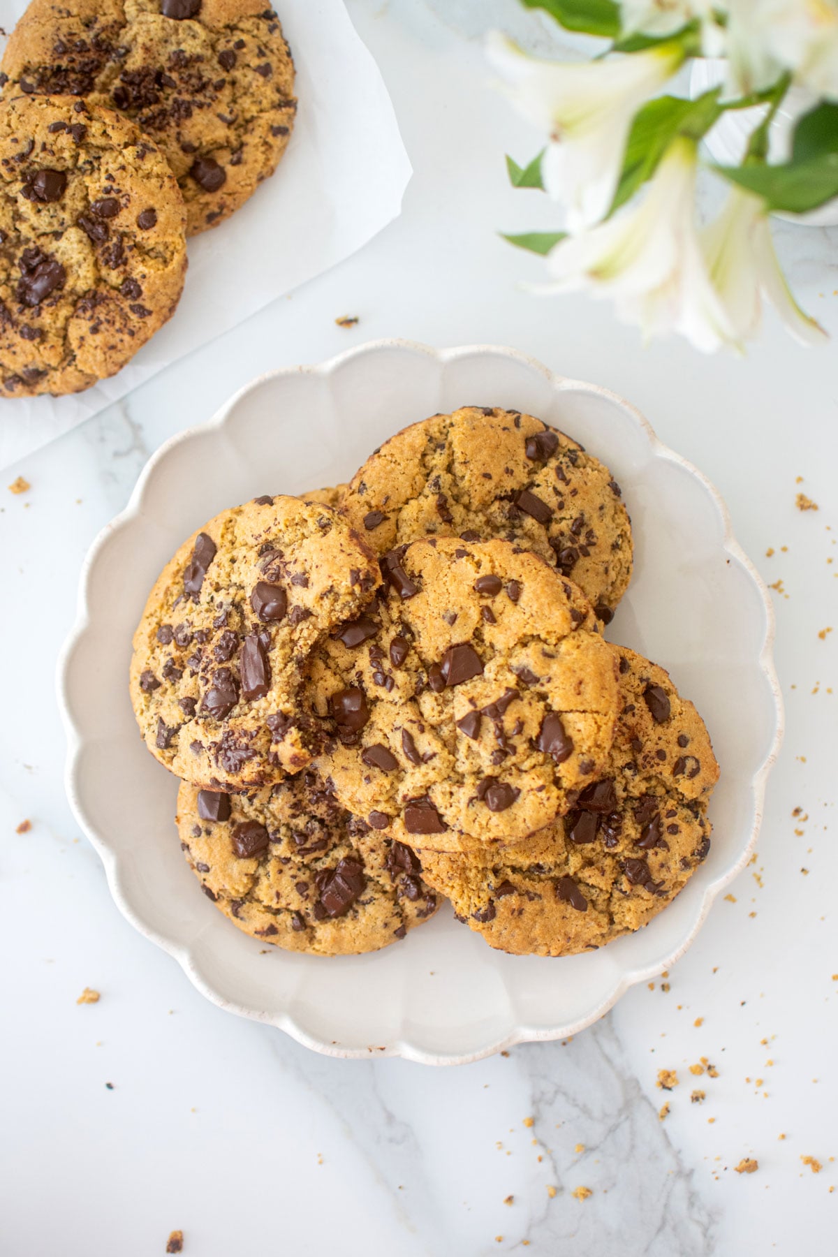 ruffle plate of vegan sourdough chocolate chip cookies on a white marble counter.