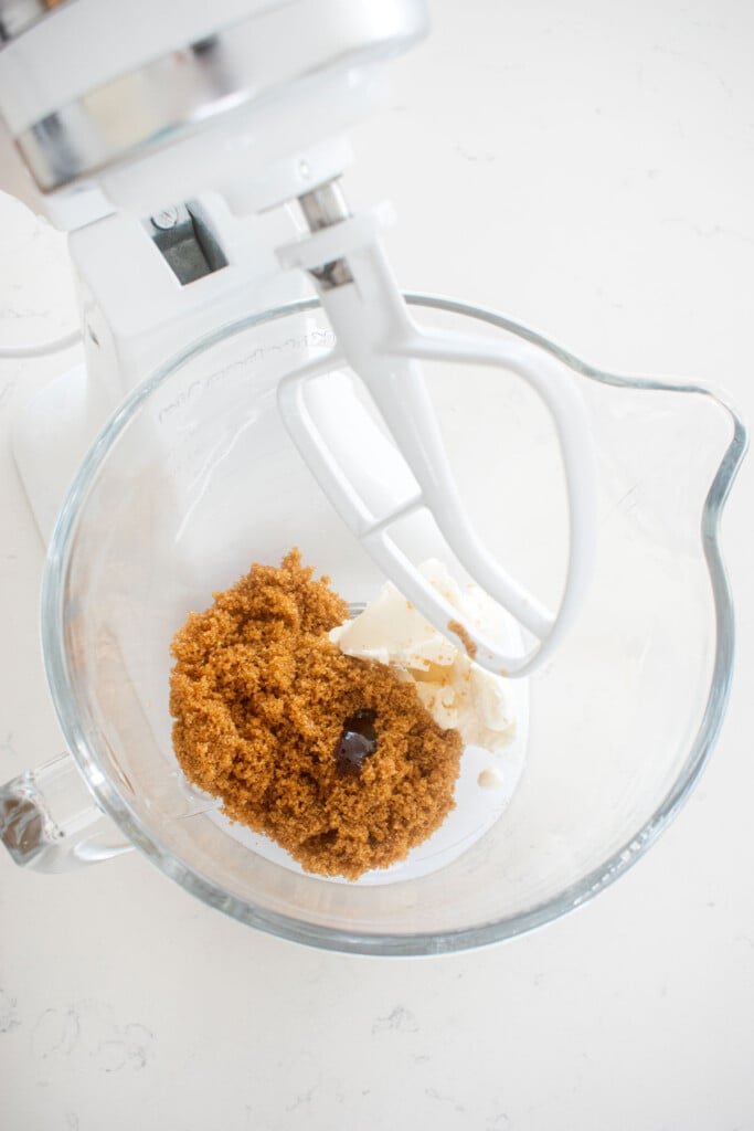 vegan butter and brown sugar in a glass mixing bowl on a white marble counter.