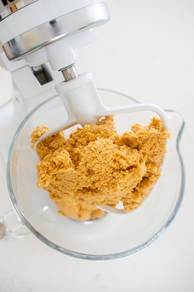 vegan sourdough chocolate chip cookie dough in a stand mixing bowl on a white marble counter.