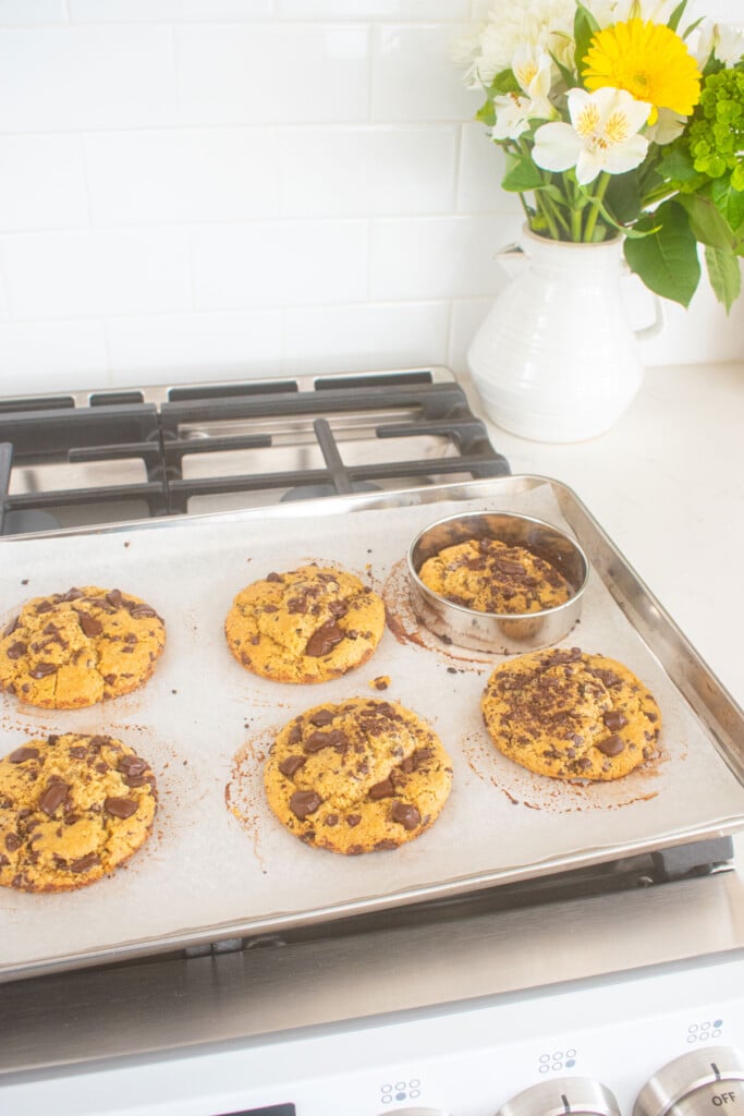 vegan sourdough chocolate chip cookies on a baking sheet on top of an oven.