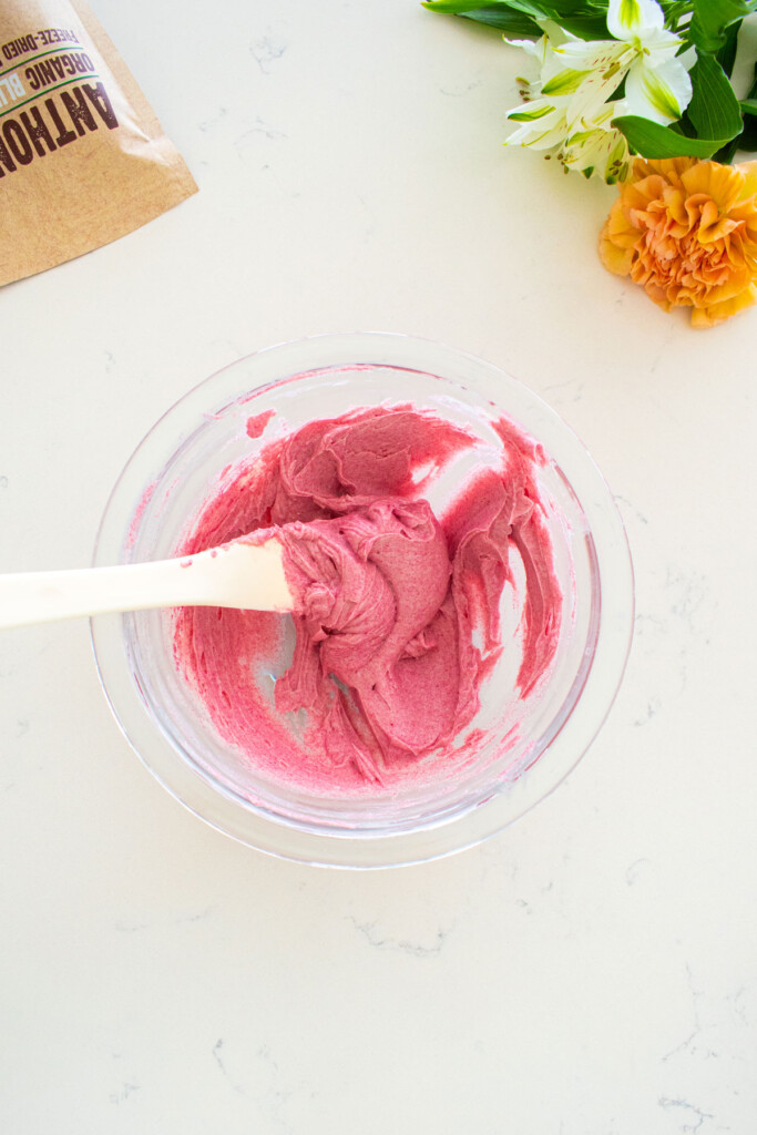 blueberry butter spread in a glass mixing bowl with a spatula on a marble counter.
