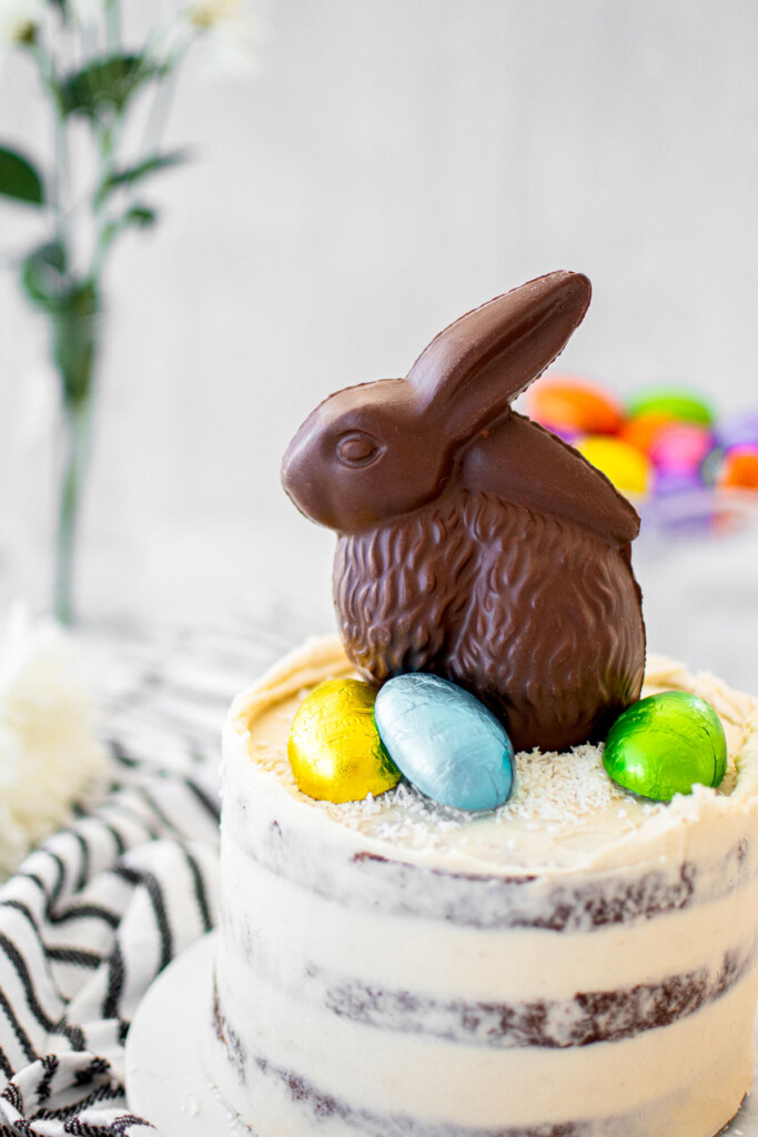 chocolate naked cake with a chocolate easter bunny and foil wrapped chocolate eggs on top.