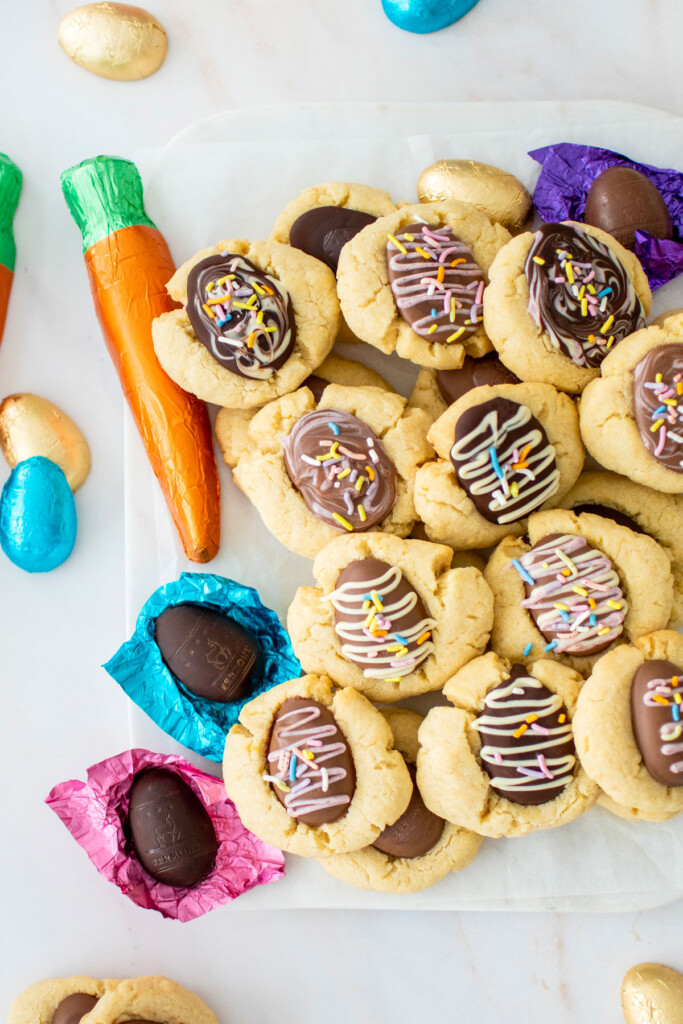easter egg thumbprint cookies on a marble serving board with chocolate eggs and carrot.